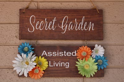 Wooden sign displaying facility name with colorful flowers