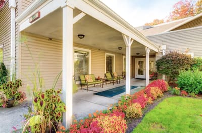 Covered entrance with seating and flower beds