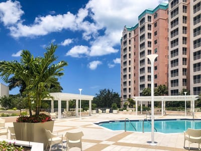 Outdoor pool area with palm trees and building in background