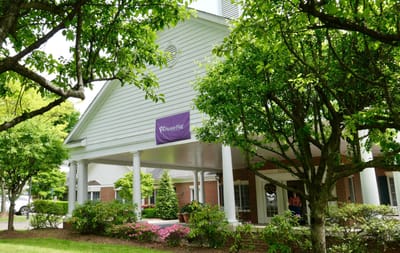 Entrance of a senior living facility surrounded by trees