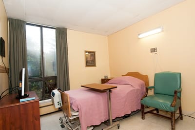 A private resident room with a bed and chair