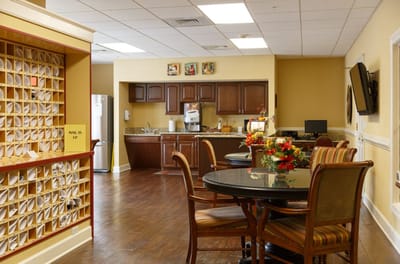 Common area with tables and kitchen in a senior living facility