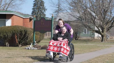 Staff member assisting resident in a wheelchair outside