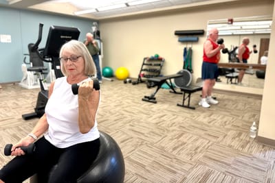 Residents exercising in a fitness room with weights