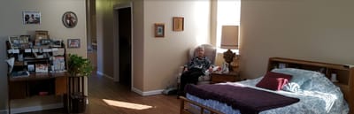 Bright resident's room with a seated elderly woman