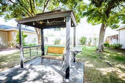 Outdoor gazebo with seating surrounded by greenery
