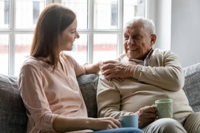 An elderly man and a woman smiling and chatting indoors
