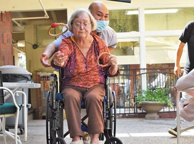 A staff member helps a resident in a wheelchair during an activity.