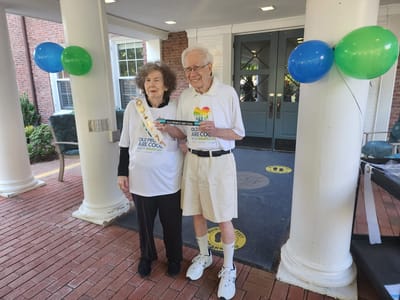 Two residents celebrating outside, holding a sign