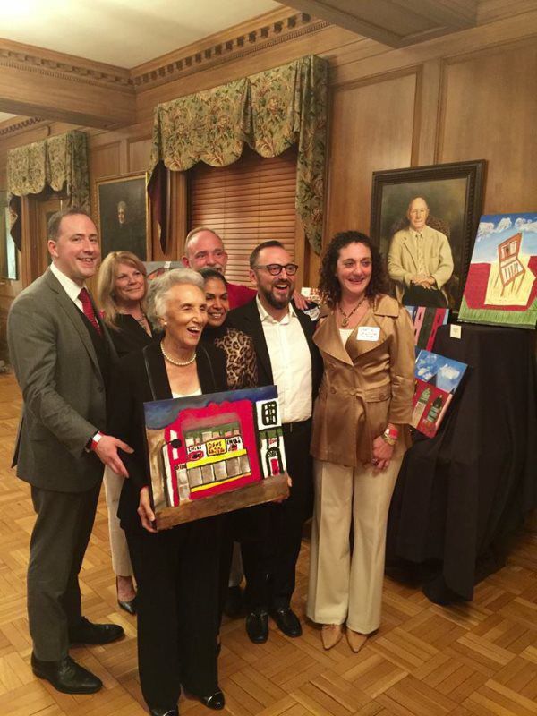 Residents and staff celebrating with artwork at an event.