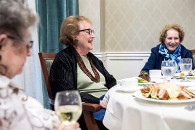 Residents enjoying a meal and conversation in a dining setting