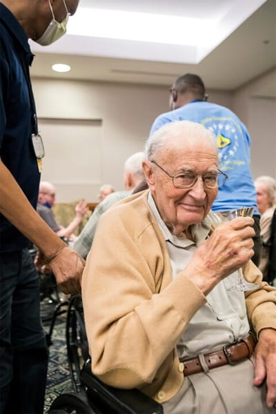 An elderly resident enjoying a drink in a common area.