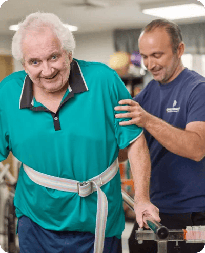 Resident receiving assistance during rehabilitation therapy