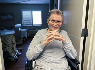 A resident seated in a wheelchair in their room
