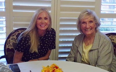 Two women smiling at a table in a common area