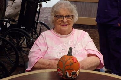 Senior resident seated at a table with a painted pumpkin