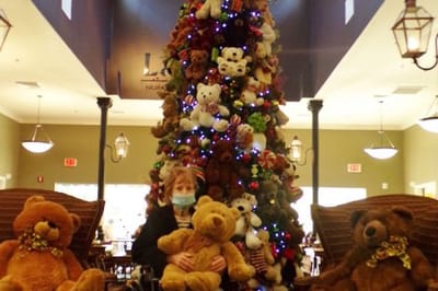 Resident interacting with teddy bears in a festive common area