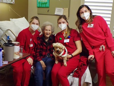 Staff and resident posing together with a dog