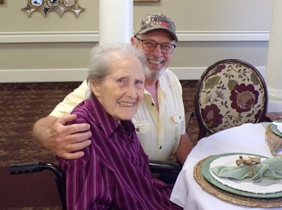 An elderly woman smiling with a man in a dining setting