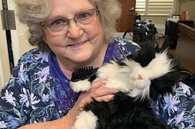 A resident smiling while holding a fluffy cat