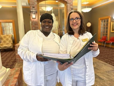 Two healthcare staff members smiling indoors