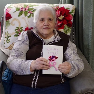 Resident holding a card that says 'YOU ARE LOVED'