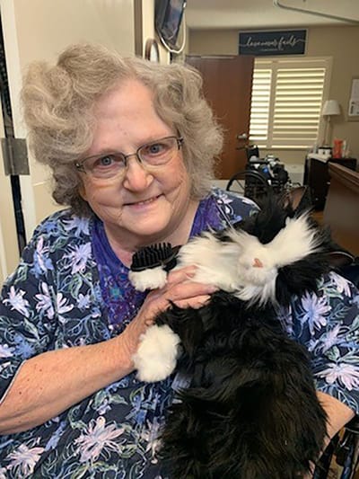 Senior woman holding a plush cat toy in a facility setting