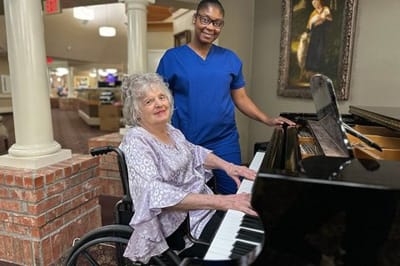 A resident playing piano in the lobby with staff