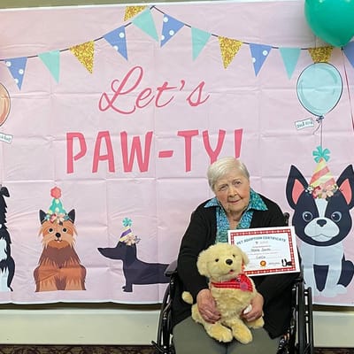 A resident holding a stuffed dog at a celebration.
