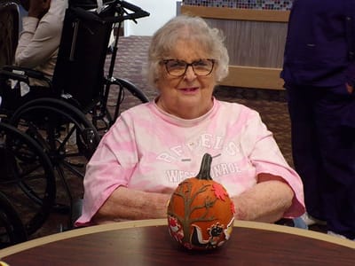 Resident with a painted pumpkin in an interior common area