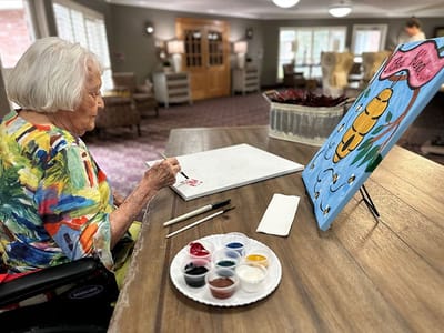 Senior resident painting in a bright activity room