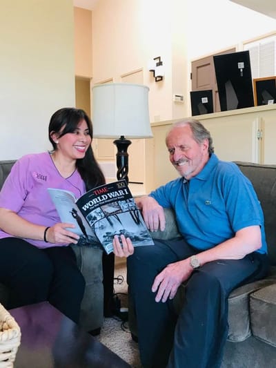 Staff member reading to a resident in a cozy living room