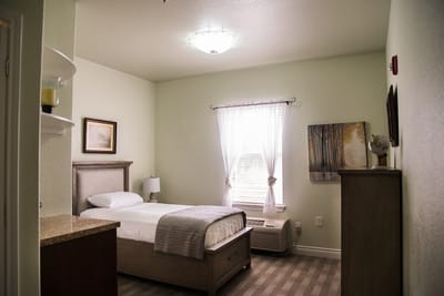 A cozy resident room with a single bed and natural light