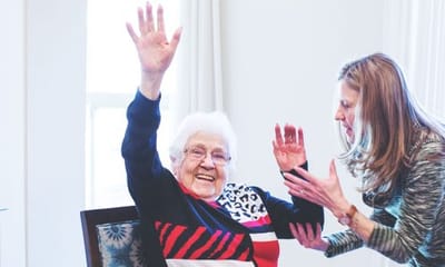 A resident joyfully interacting with staff in a common area