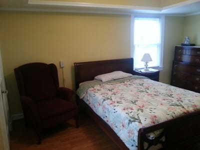 A cozy resident room with a bed and armchair