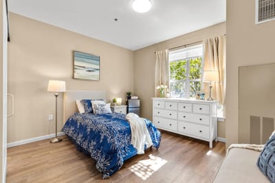 Cozy resident room with a blue bedspread and window