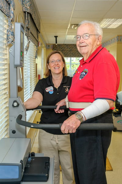 Staff assisting a resident with exercise equipment