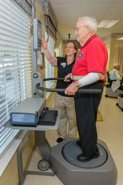 A resident using exercise equipment with staff assistance