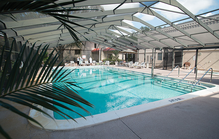 Indoor pool area with lounge chairs and a covered roof