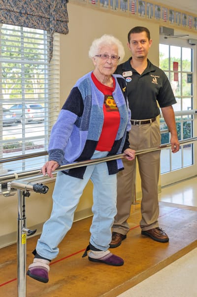 A staff member assists a resident with mobility training