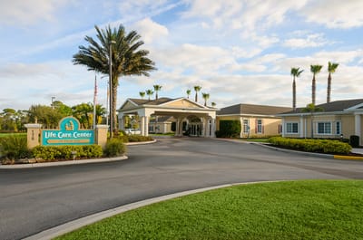 Entrance of Life Care Center of Palm Bay with palm trees