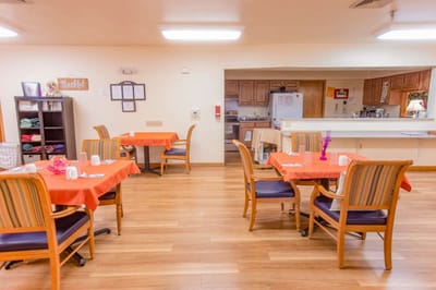 Dining area with orange table settings and kitchen visible