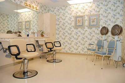 Beauty salon area with styling chairs and floral wallpaper