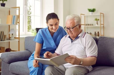 A caregiver and a resident reading together on a couch
