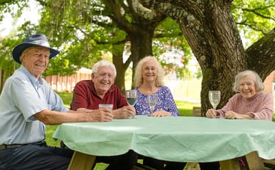 Seniors enjoying drinks outdoors under a tree