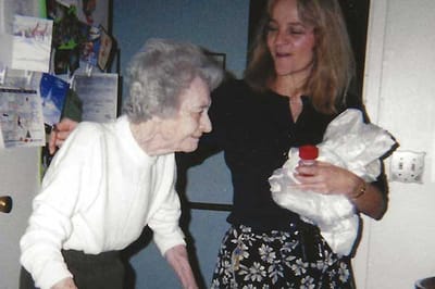 An elderly woman assisted by a caregiver indoors