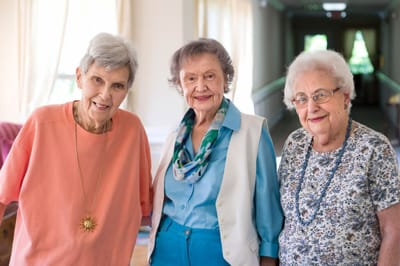 Three female residents smiling in a hallway