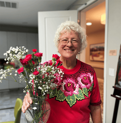 Resident holding a vase of flowers in a common area