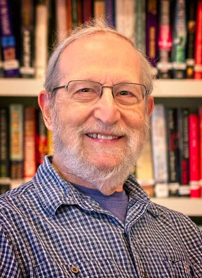 A smiling elderly man in a library setting