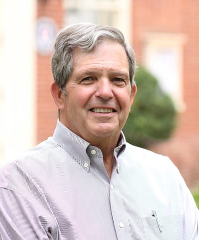 A smiling older man in a collared shirt